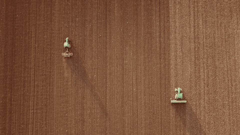 An aerial view of farm machinery working a field in animal.